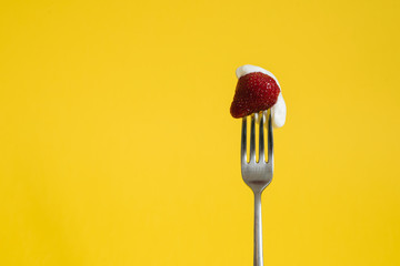 Macro shot of ripe strawberries on a fork with sour cream. Closeup red berry with yellow background - 352600209