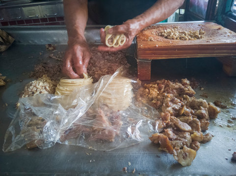 Elaboraci&oacute;n de tacos tradicionales de diversos tipos de carnita, como barbacoa, oreja, sesos entre otros, se alcanza a ver las carnitas, la tabla de cortar carne y las manos de el taquero o cocinero.