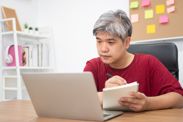 Asian freelance studying for new skills from the internet at home after working is finished. Concept of learning online and new lifestyle, internet technology, and information for a new normal life