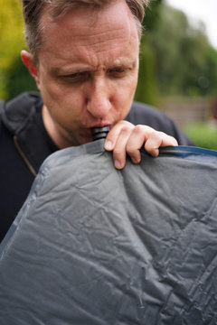 Close Up Of Man Blowing Up A Self Inflatable Sleeping Pad For Camping  