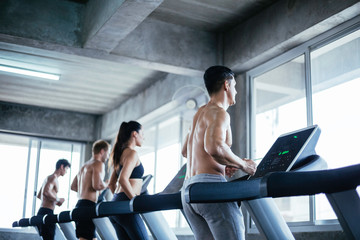 Fototapeta na wymiar Soft focus group of Caucasian athletic people running workout on treadmill. side view of muscular men and woman do fitness exercise training at gym. healthy and lifestyle preventing Coronavirus