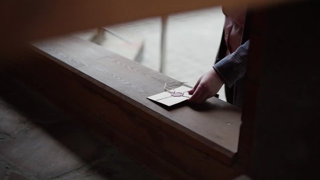 Female hand spreads a craft letter in an envelope with a wax seal on a wooden shelf on the street