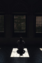 mujer solitaria mirando por la luz que entra por la ventana en un cuarto oscuro