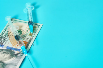 Fototapeta na wymiar Banknote of 100 usd and syringe on green background. Corruption in medicine. Purchasing medications in pharmacy. Drugs donations. Payment for treatment. Health сare concept