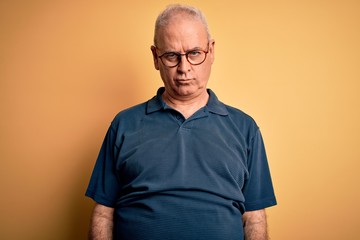 Middle age handsome hoary man wearing casual polo and glasses over yellow background depressed and worry for distress, crying angry and afraid. Sad expression.