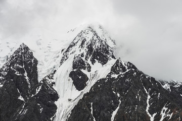Atmospheric minimalist alpine landscape with massive hanging glacier on snowy mountain peak. Big balcony serac on glacial edge. Low clouds among snowbound mountains. Majestic scenery on high altitude. © Daniil