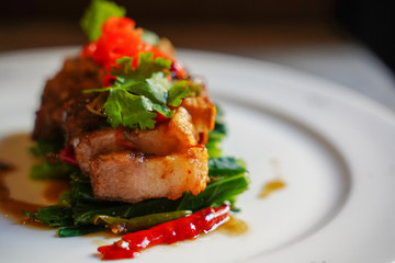 Close up crispy Pork Belly Stir Fry with Chinese Kale on white plate, side view of crispy pork belly