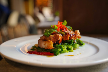 Crispy Pork Belly Stir Fry with Chinese Kale on white plate, side view of crispy pork belly