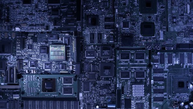 The main processor on the large board is connected to other circuits via wires glowing with blue light. Closeup