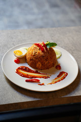 Tom Yum Fried Rice with chicken and boiled egg on white plate, side view of Thai fired rice