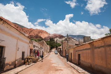 calles de purmamarca en el norte argentino, calle de tierra con montañas de fondo con cielo con nubes