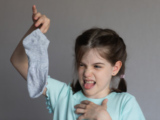 little girl holds a dirty sock that smells bad