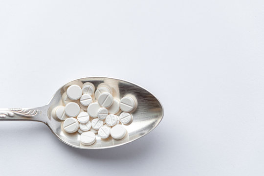 Medicine and health, treatment, pharmacy, coronavirus, pandemic, epidemic concept - layout one silver big tablespoon with different pills and capsules on a white background copy space.