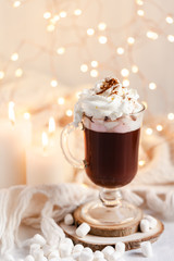 Winter hot drink: hot chocolate with marshmallow and whipped cream. Delicious sweet beverage. Christmas lights on background. Cozy home atmosphere, holiday festive mood. Close up, macro