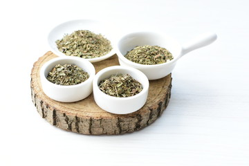 Chopped dried leaves of basil leaves on white wooden background