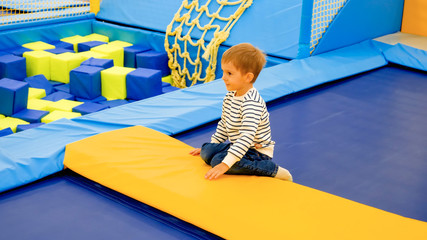 Cute little boy having fun and playing on trampolines at amusement park