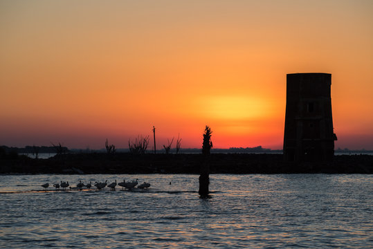 atardecer sobre el lago y una torre muy rojo muy naranja silueta de torreon