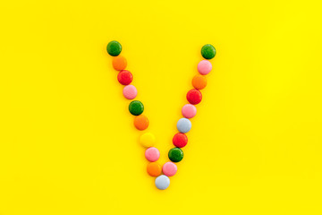 Obraz premium Letter V - alphabet made with sweets on yellow from above