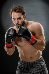 Fototapeta na wymiar A man in Boxing gloves. A man Boxing on a black background. The concept of a healthy lifestyle