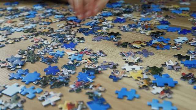 Family makes a puzzle at home on the floor. Top view, slow motion