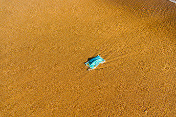 Abandoned protective facial mask in prevention vs virus infection on the natural outdoors beach background.