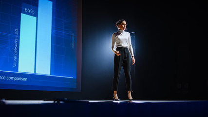 On-Stage Successful Female Speaker Presents Technological Product, Uses Remote Control for...
