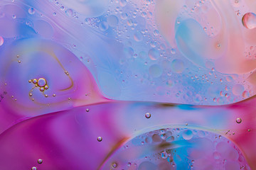 Close-up of the movement of oil droplets on the water surface. Colorful abstract macro background...