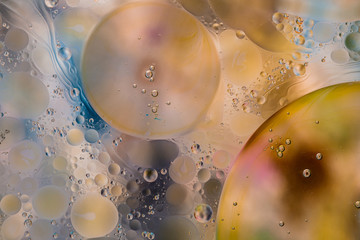 Close-up of the movement of oil droplets on the water surface. Colorful abstract macro background...