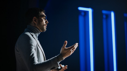 Portrait of Motivational Speaker Wearing Glasses, Talking about Happiness, Self, Success and How Better More Productive Self. Tech Startup Presenter Pitching. Cinematographic Light - obrazy, fototapety, plakaty
