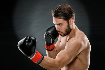 A man in Boxing gloves. A man Boxing on a black background. The concept of a healthy lifestyle