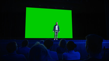 On Stage, Keynote Speaker Presents New Product to the Audience, Behind Him Movie Theater with Green...