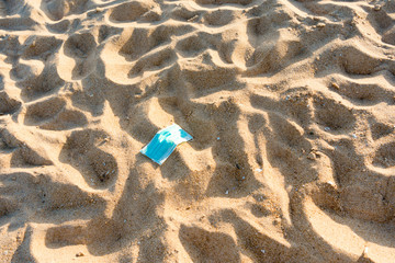 Abandoned protective facial mask in prevention vs virus infection on the natural outdoors beach background.