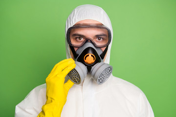 Close-up portrait of his he nice content serious disinfectant wearing touching fixing gas mask anti dust toxic pollution ecology quarantine isolated over green pastel color background