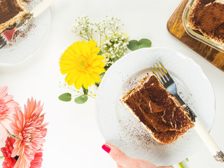 Traditional coffee tiramisu dessert with mascarpone cheese and cocoa powder served on plates on white wooden table
