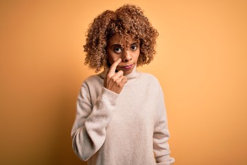 Young beautiful african american woman wearing turtleneck sweater over yellow background Pointing to the eye watching you gesture, suspicious expression