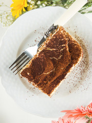 Traditional coffee tiramisu dessert with mascarpone cheese and cocoa powder served on plates on white wooden table