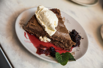 Torta de chocolate con frutos rojos y crema sobre un plato blanco