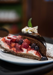 Torta de chocolate con frutos rojos y crema sobre un plato blanco
