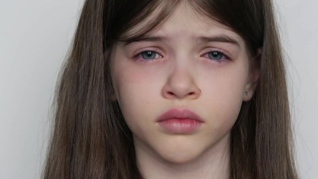 close-up portrait of a little beautiful crying girl on a white background