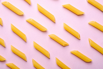 Italian pasta, raw penne tube macaroni pattern on pink background, top view, abstract food