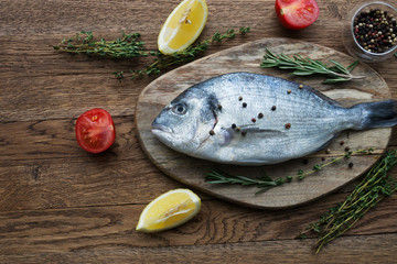 Raw fish cooking and ingredients. Dorado, lemon, herbs and spices. Top view on stone table