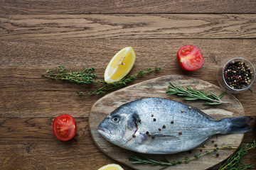 Raw fish cooking and ingredients. Dorado, lemon, herbs and spices. Top view on stone table