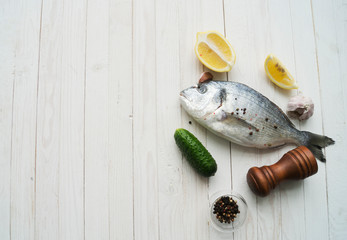 Raw fish cooking and ingredients. Dorado, lemon, herbs and spices. Top view on stone table