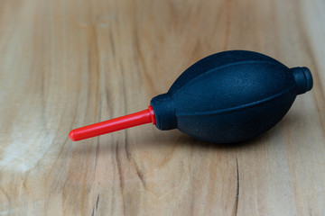 Camera cleaning kit, black and red pump on a wooden table.