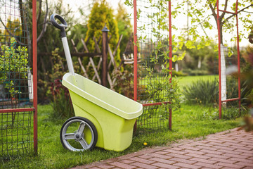 A plastic garden wheelbarrow sits on a freshly mown lawn in the garden
