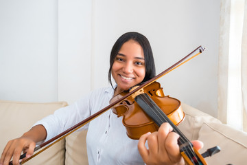 A pretty young Latina teenager playing the violin; close-up