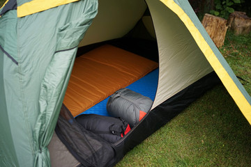 Close up look into a camping tent with sleeping bags and self inflatable sleeping pads          