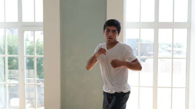 Kickboxer training at home. Athlete boxing to the camera. Medium shot with camera shake when a boxer hits. Self defense, sambo wrestler.