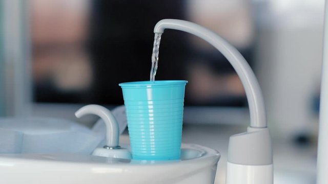 Water pouring into cup in dentists office
