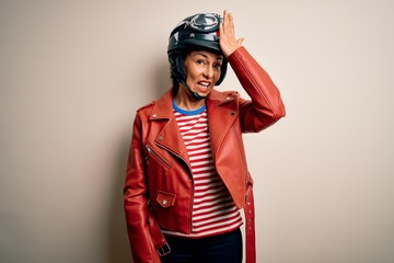 Middle age motorcyclist woman wearing motorcycle helmet and jacket over white background surprised with hand on head for mistake, remember error. Forgot, bad memory concept.